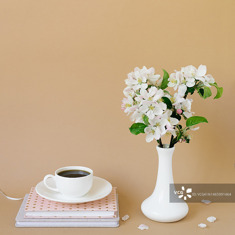 白色花瓶中美丽的白色苹果树花朵、笔记本和一杯茶，明斯克，白俄罗斯图片素材