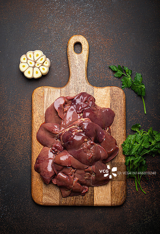 深色乡村背景木制砧板上的生鸡肝图片素材