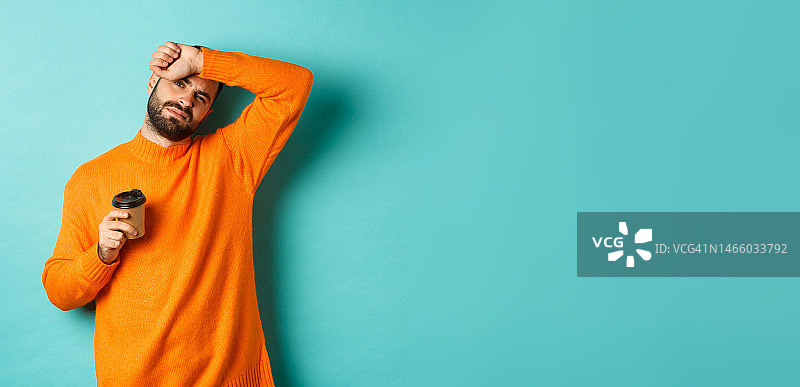 疲惫的成年男子工作间隙喝咖啡，擦汗图片素材