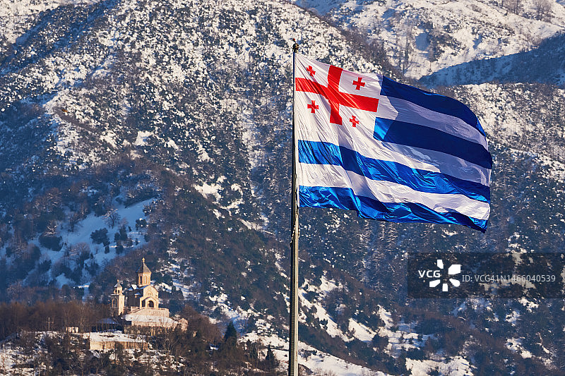 阿扎尔自治共和国国旗，背景是雪山和格鲁吉亚传统建筑风格的教堂图片素材
