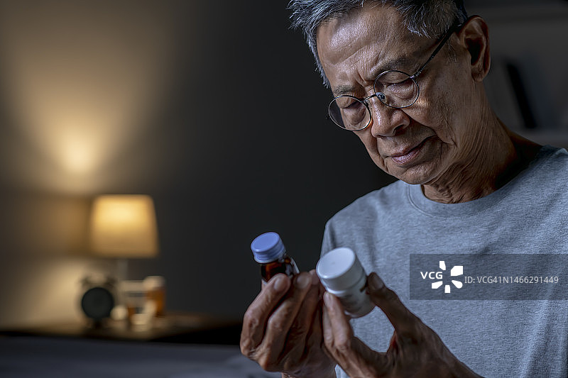 在卧室服药的亚洲老年男性图片素材