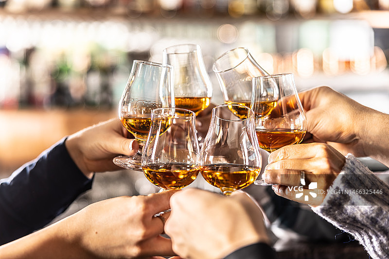 一群朋友用朗姆酒、白兰地、威士忌或干邑酒杯敬酒图片素材