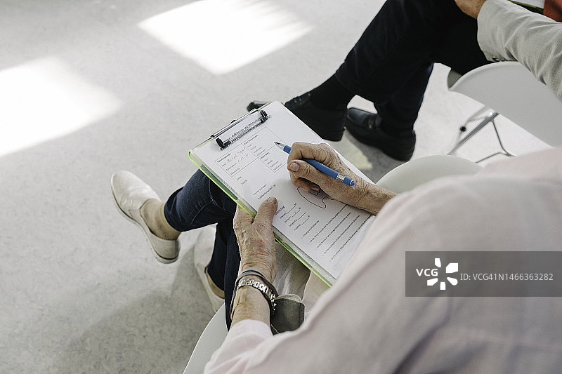 年长的病人拿着医疗表格的特写图片素材