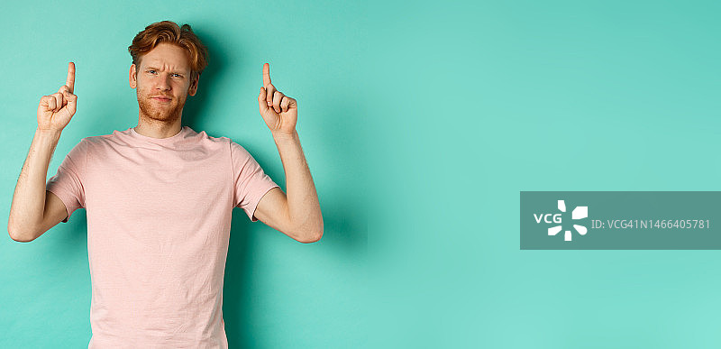 怀疑且失望的红发男人指着上方，皱着眉头图片素材