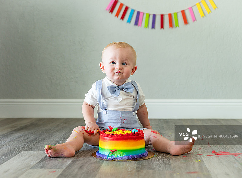凌乱的男宝宝一周岁生日，面对不确定的生日蛋糕，滑稽可爱的孩子图片素材