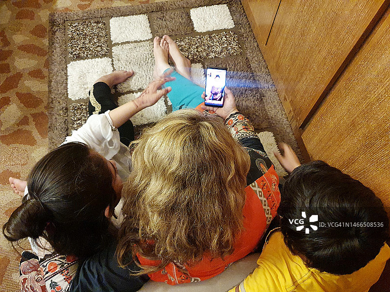 母亲和两个孩子在家用智能手机快乐地进行视频通话图片素材