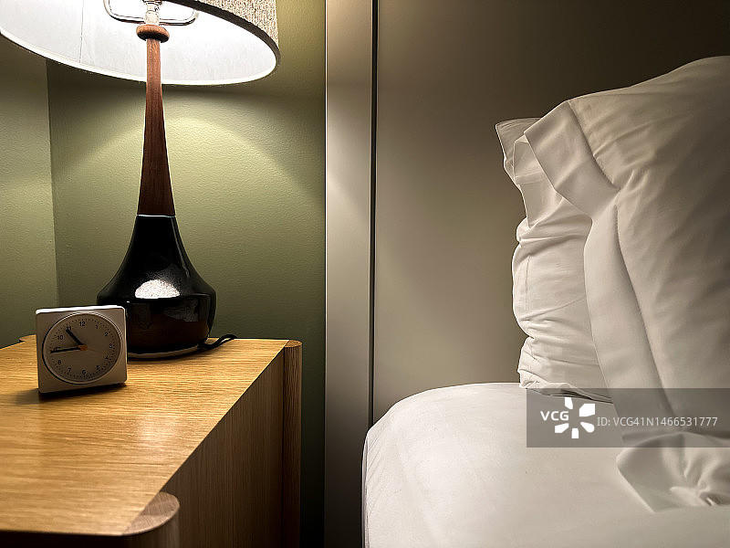 带闹钟和床头灯的舒适床铺图片素材
