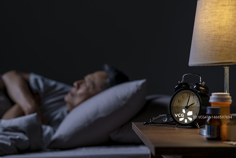 沮丧的亚洲老年男人躺在床上失眠图片素材