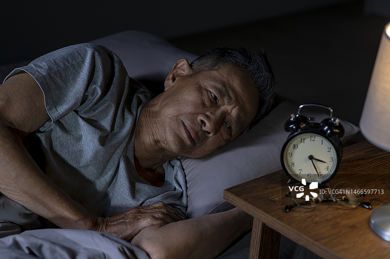 抑郁的亚洲老年男子躺在床上无法入睡，因为失眠图片素材