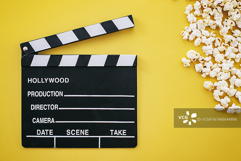 黄色背景上的爆米花和电影场记板图片素材