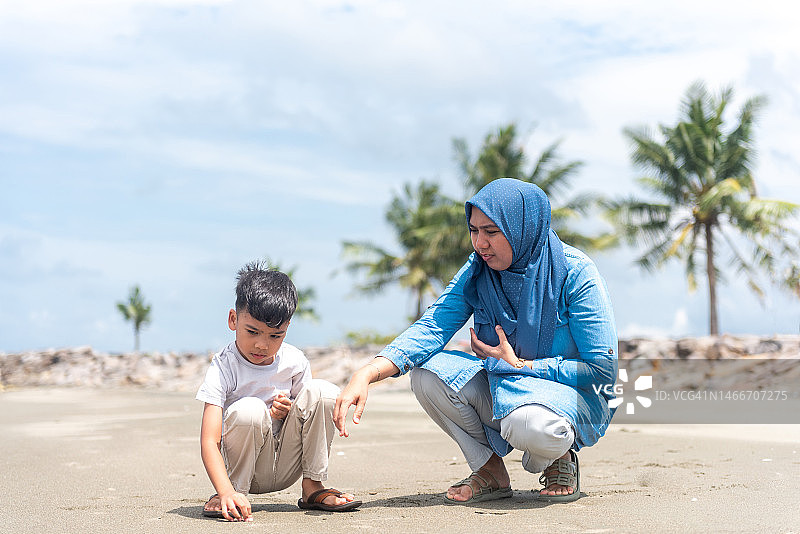 母子在海滩上寻找贝壳图片素材