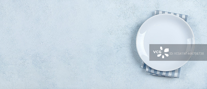 餐桌布置背景：蓝色石桌上的浅色盘子和蓝色格子桌布，哈萨克斯坦图片素材