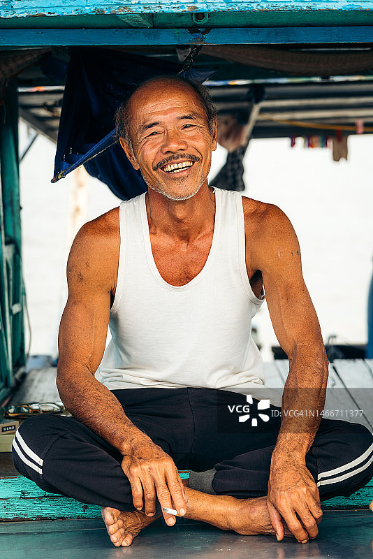 在湄公河三角洲水上市场船屋上的快乐越南老人图片素材