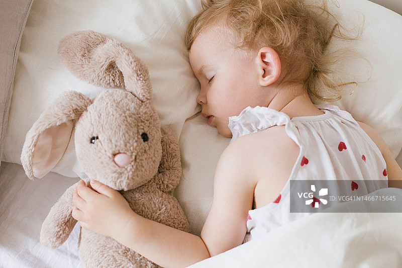 小女孩抱着玩具兔子甜蜜地睡着图片素材