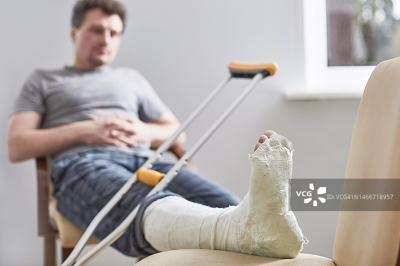 年轻男子腿部石膏特写，跑步受伤或摔倒，俄罗斯图片素材