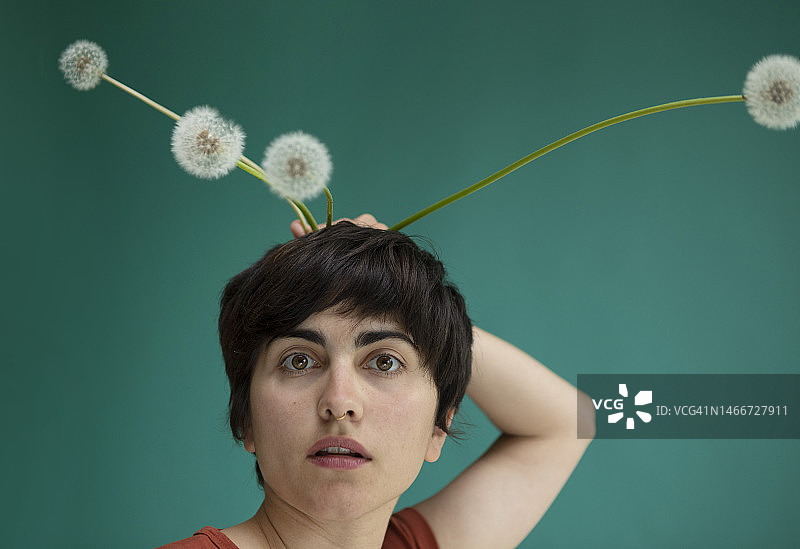 女人在绿色背景下手持蒲公英图片素材