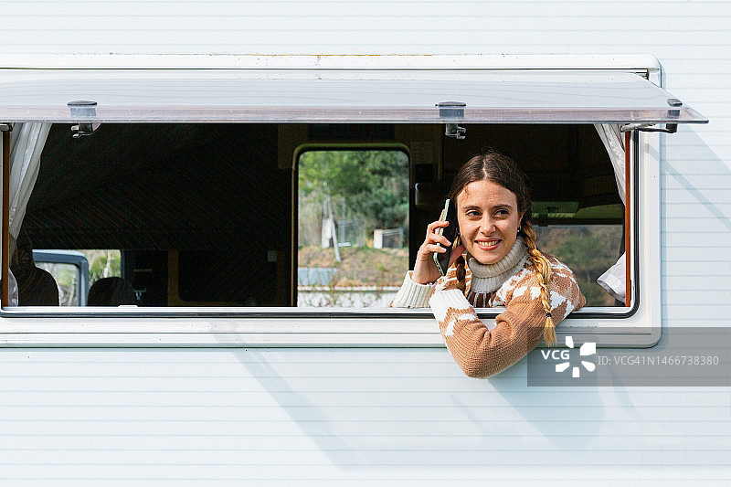 坐在房车里用手机聊天的微笑女人图片素材