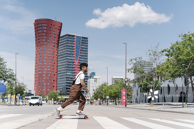 年轻男人在城市斑马线上玩滑板图片素材