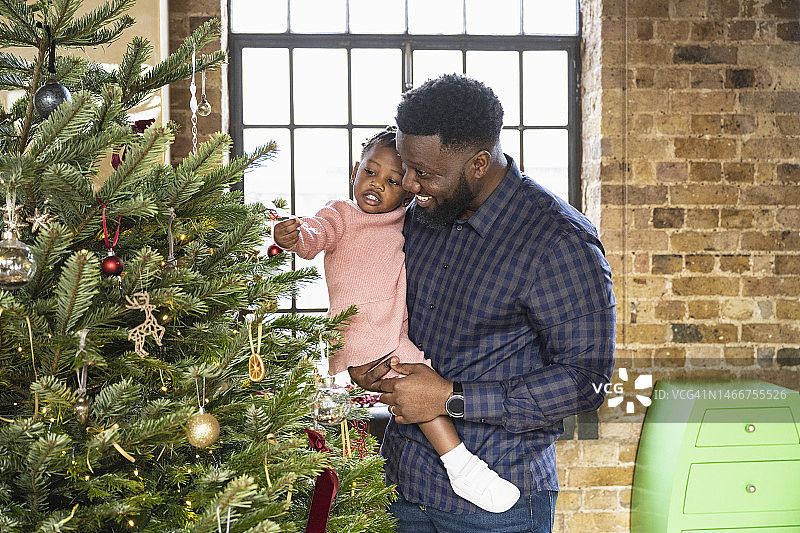 父亲和女儿欣赏圣诞树上的装饰品图片素材