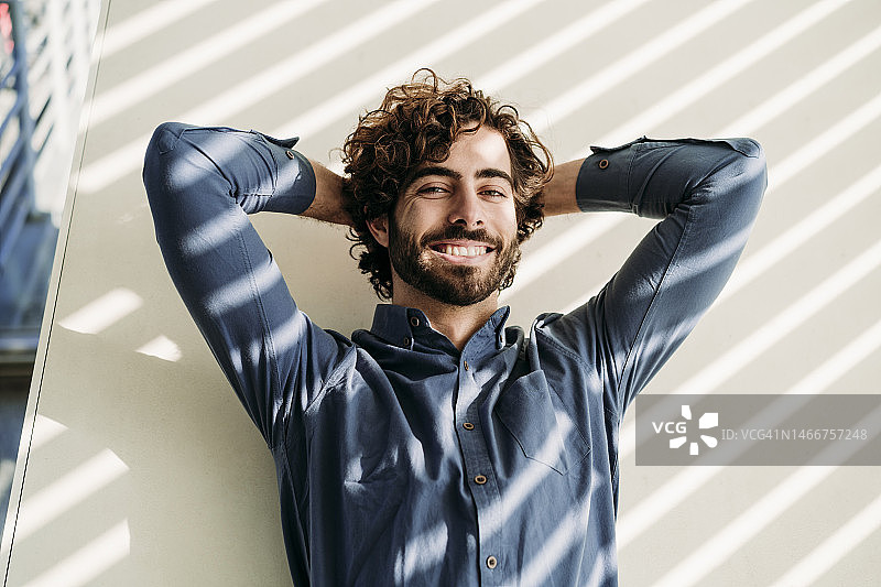 快乐的商人靠墙双手抱头图片素材