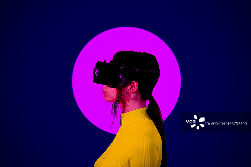 年轻女子戴VR眼镜，背景为黑色粉色圆圈图片素材