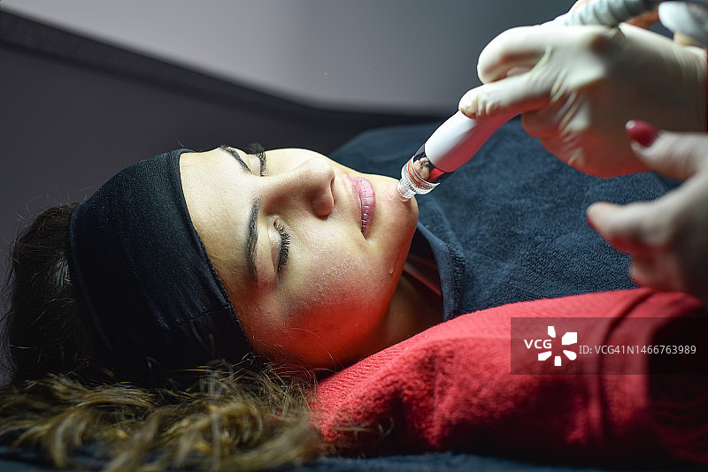 年轻女子在美容诊所接受面部护理图片素材