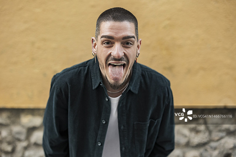 对着墙壁吐舌头的快乐男人图片素材