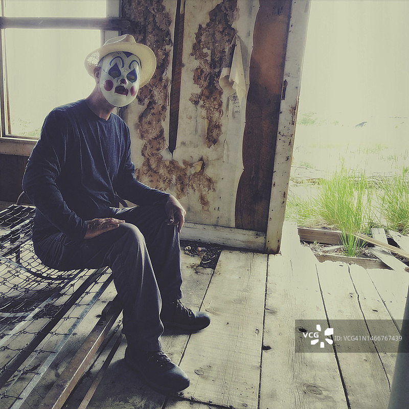 在旧房子里戴着小丑面具的男人图片素材