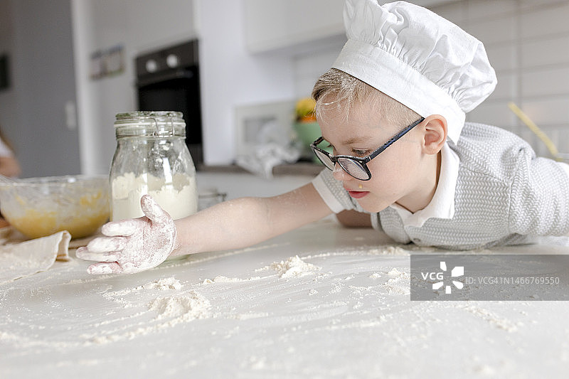 男孩在厨房的桌子旁玩面粉图片素材