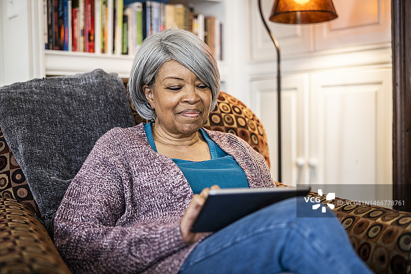 年长的女人在家中使用平板电脑图片素材