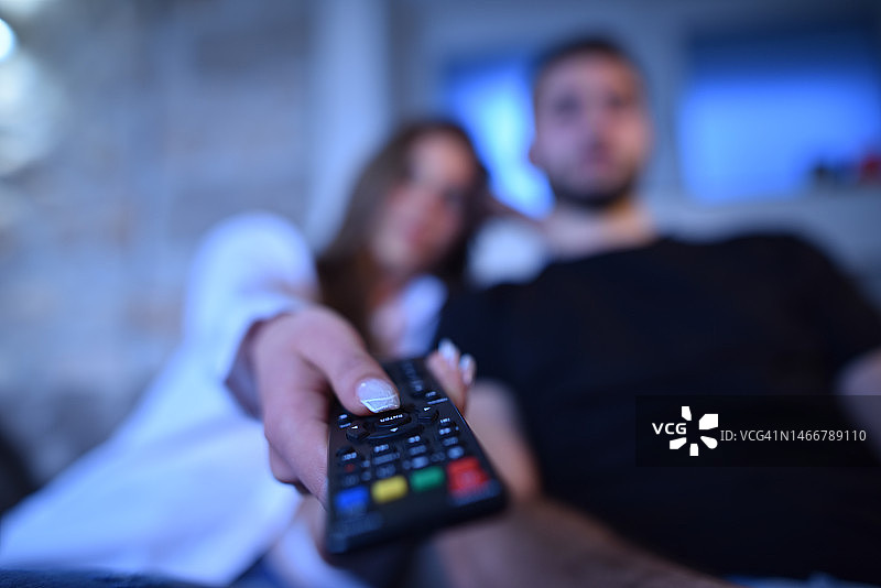 特写：情侣在家看电视遥控器图片素材