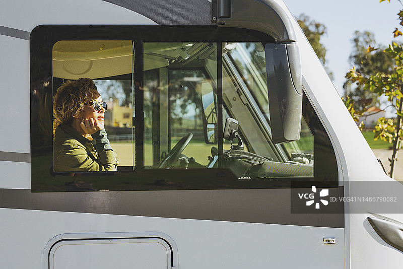 在阳光明媚的日子里坐在露营车里沉思的中年妇女图片素材