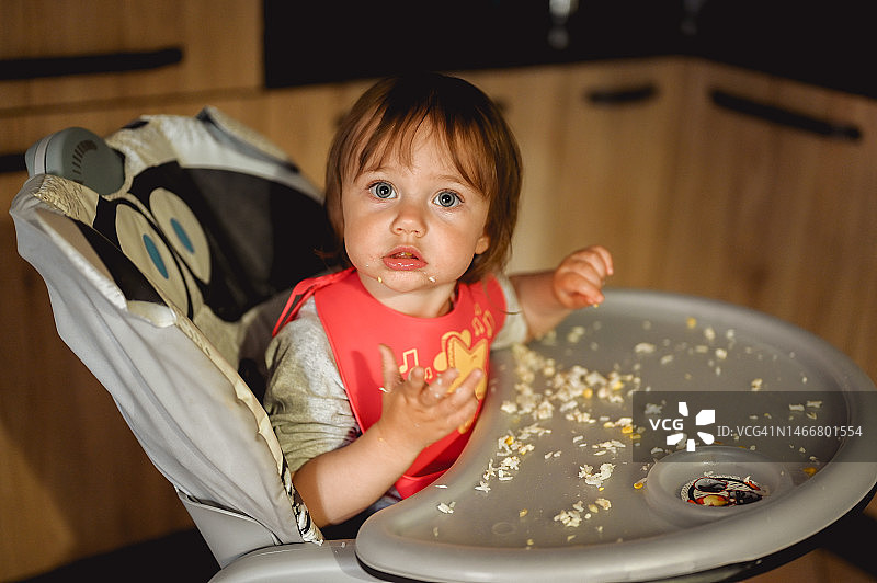 坐在儿童餐椅上吃饭的小女孩图片素材