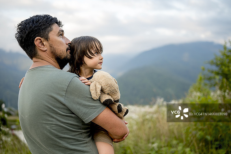 假期里，父亲抱着拿着泰迪熊的儿子图片素材