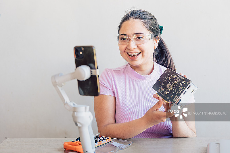 年轻女子通过手机视频直播电子产品课程图片素材