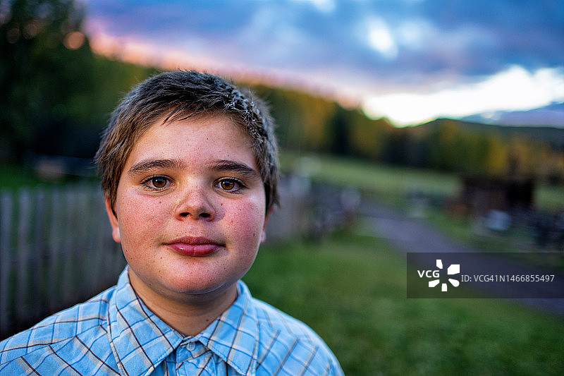 科罗拉多州西南部农场少年在牧场上的肖像，背景是引人注目的彩色日落图片素材
