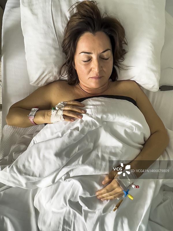 年轻女子在医院病床上术后睡觉，顶视图图片素材