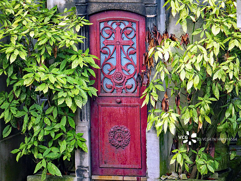 巴黎拉雪兹公墓一扇带有宗教符号的旧红色风化金属门图片素材