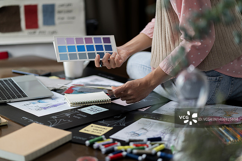 亚洲女时装设计师在工作室设计草图并选择面料样品图片素材