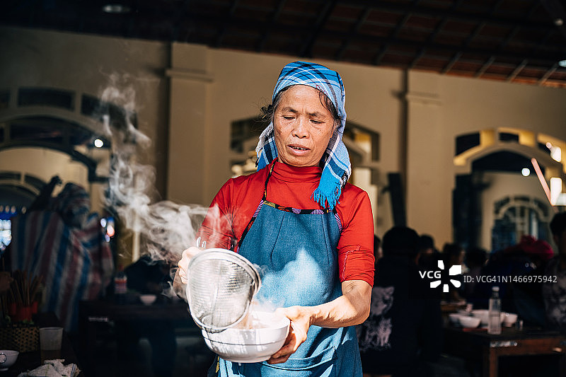 越南巴哈市场：当地老年妇女在煮面条图片素材