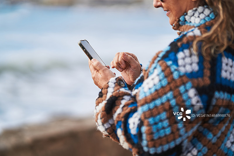 在海边使用智能手机的中年妇女图片素材
