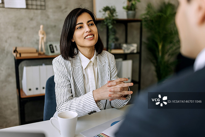 年轻漂亮的女商人与同事在办公室交谈图片素材