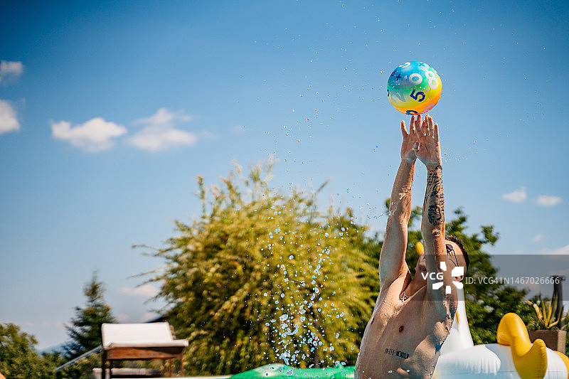 在游泳池里打排球的年轻男人图片素材