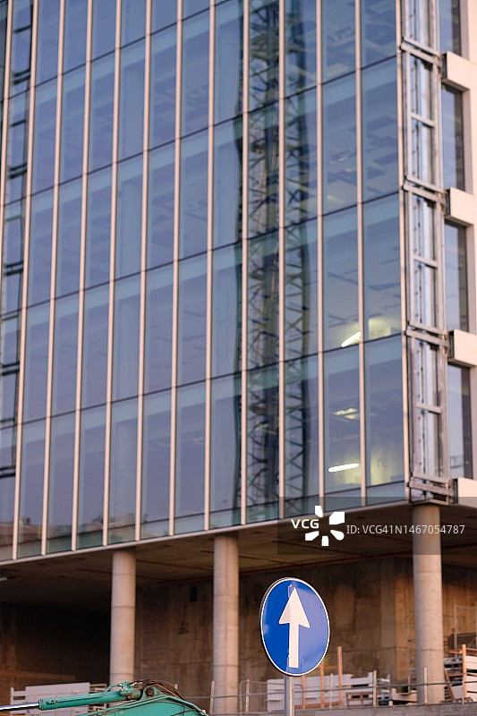 带有彩色玻璃窗的摩天大楼外墙，指向上方的路标图片素材