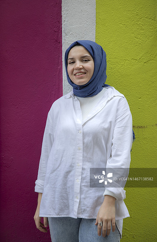 年轻女子站在彩色墙前图片素材