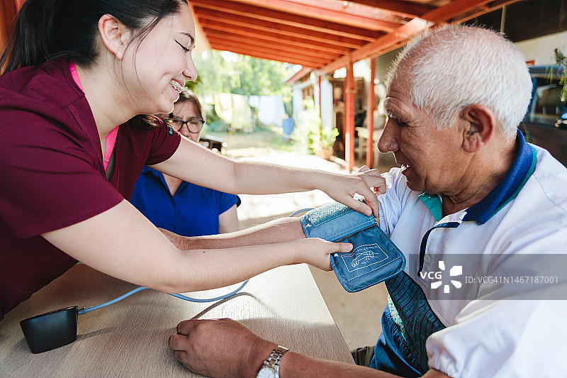 乡村医疗访视员为年长的拉丁裔男性农民测量血压图片素材