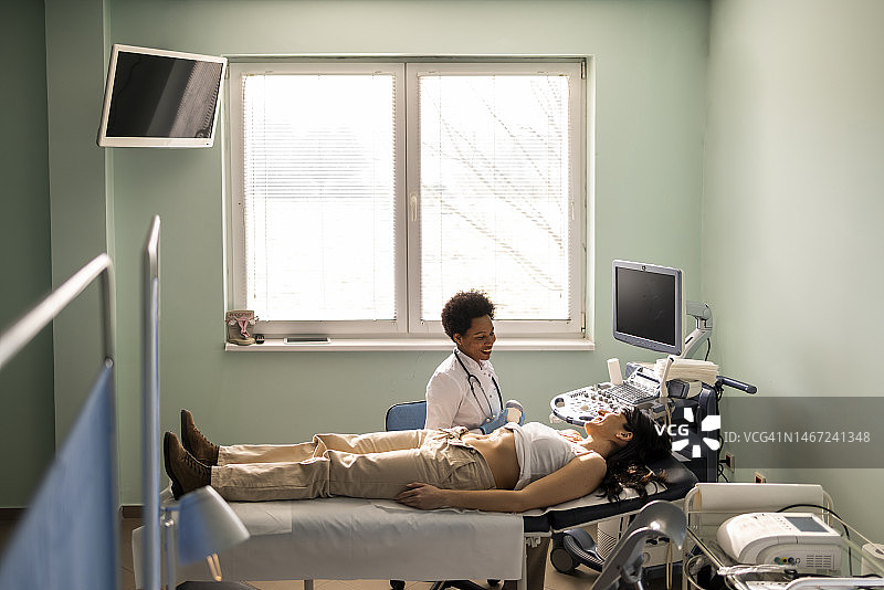 医生在诊所用超声波扫描检查女患者的腹部图片素材