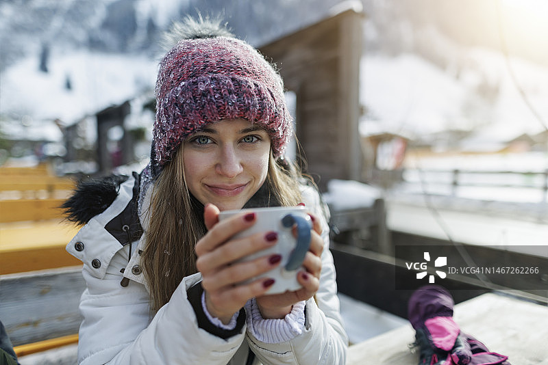 冬日阳光明媚，少女在户外餐厅享用热茶图片素材