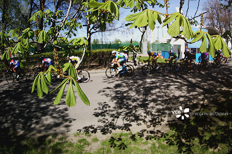 在模糊的茂盛树叶背景下，身份不明的自行车手快速骑行图片素材