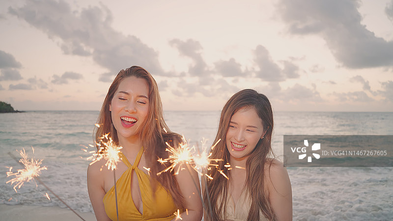 快乐的女人在海滩上玩烟花图片素材